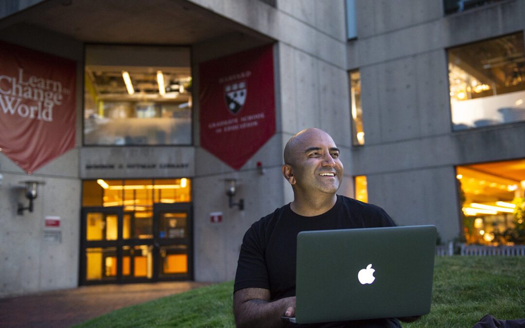 Student sitting in front of Harvard School of Education working on a laptop